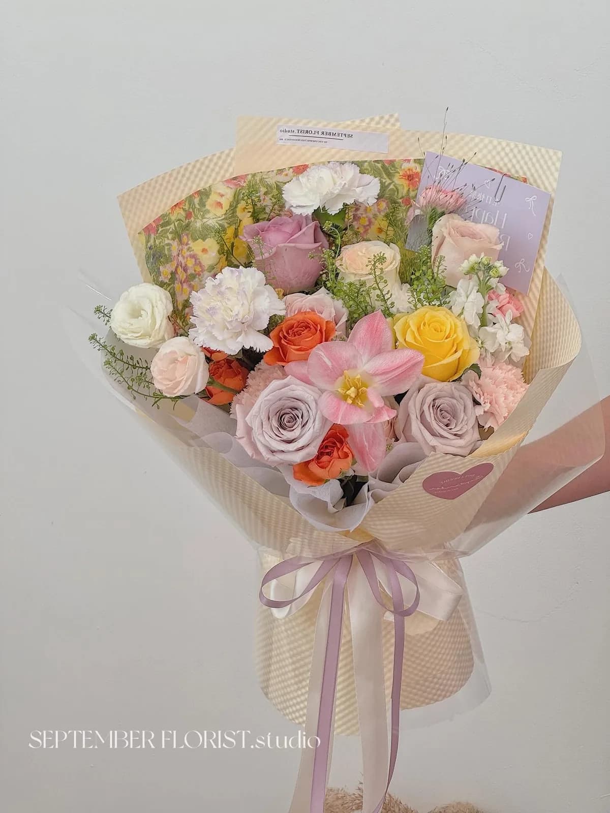 A pastel bouquet of tulips and roses being wrapped